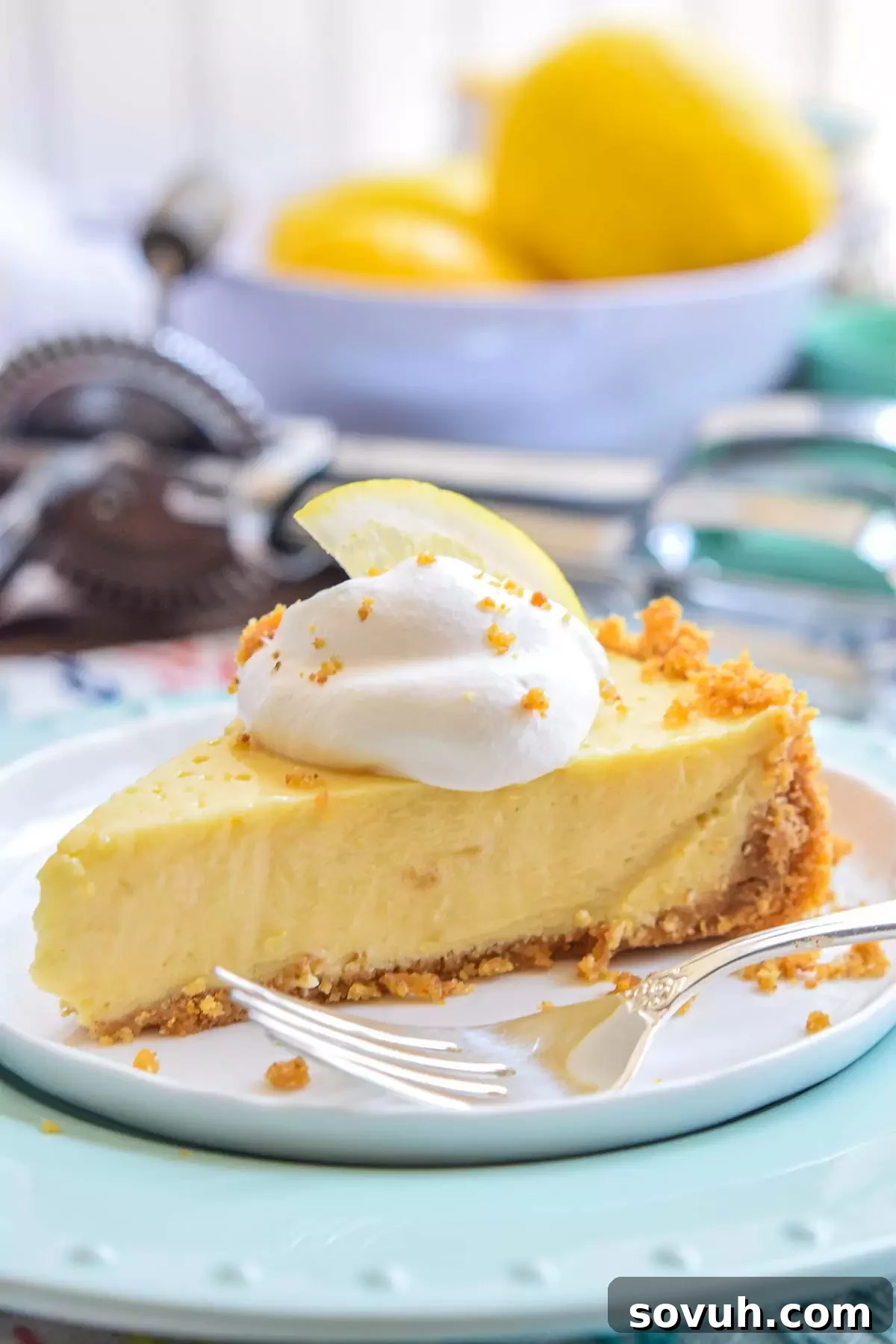 Zesty Lemon Icebox Pie 5 A perfectly sliced Lemon Icebox Pie on a white plate with a fork beside it, highlighting the smooth lemon filling and textured graham cracker crust.