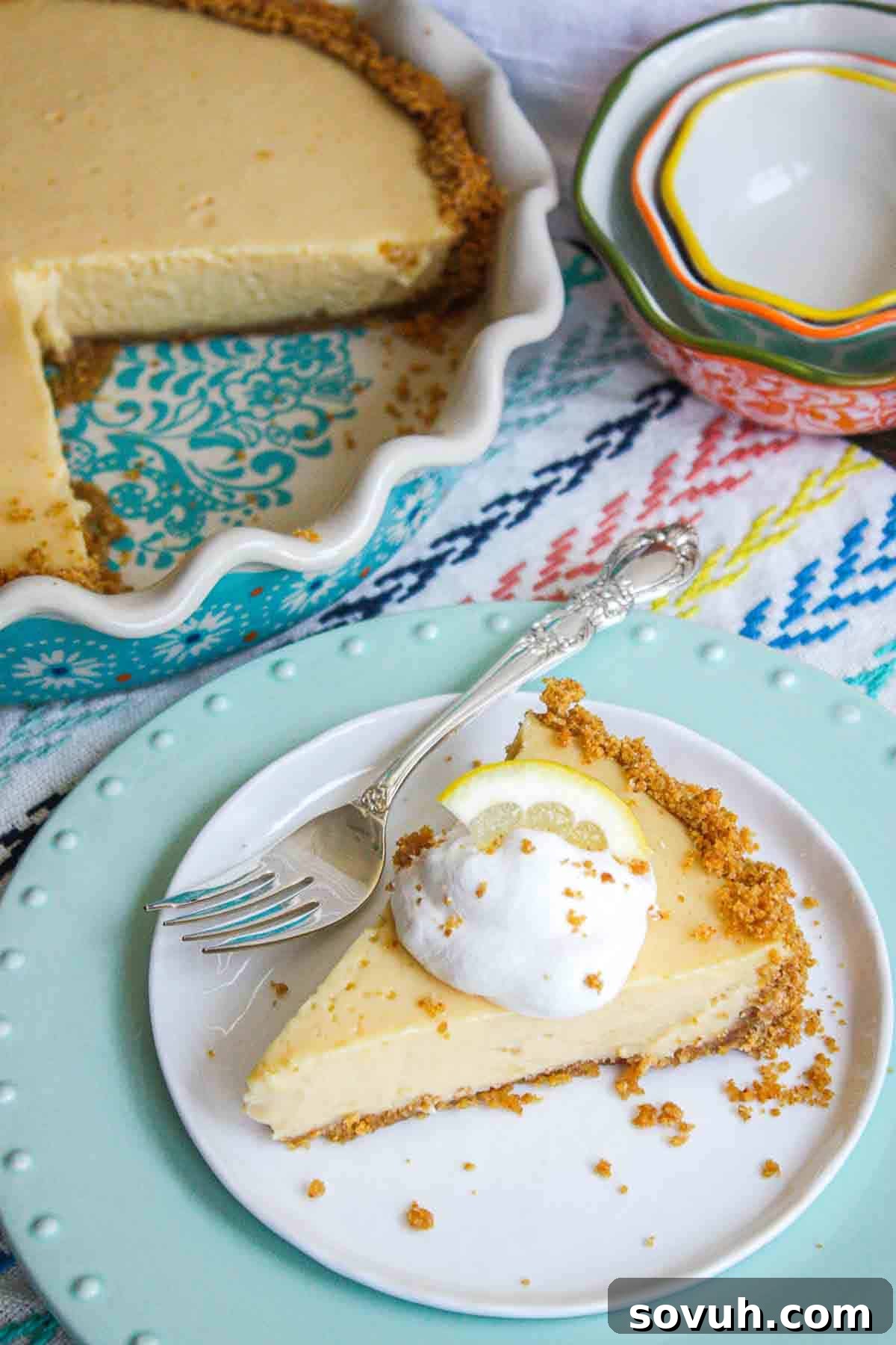 Zesty Lemon Icebox Pie 6 A beautiful, whole Lemon Icebox Pie in a baking dish, with a single slice on a plate in the foreground, ready for serving.