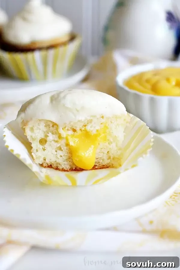 A cross-section of a coconut mango cupcake, showcasing the moist cake and the vibrant mango curd filling, ready to be enjoyed.