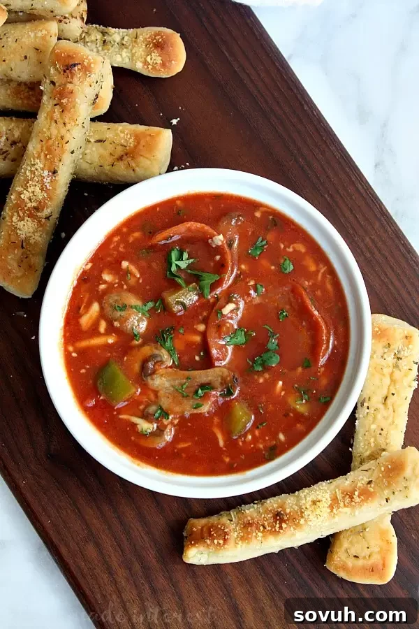 Full vertical shot of Slow Cooker Pizza Soup with melted cheese and toppings, ready to enjoy.