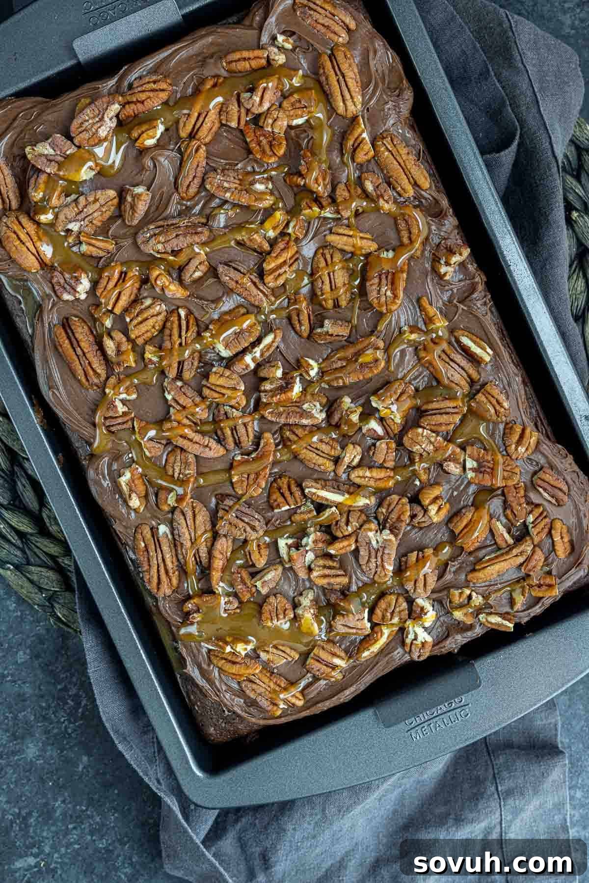 Finished Chocolate Turtle Cake, beautifully frosted, drizzled with extra caramel, and generously topped with chopped pecans.