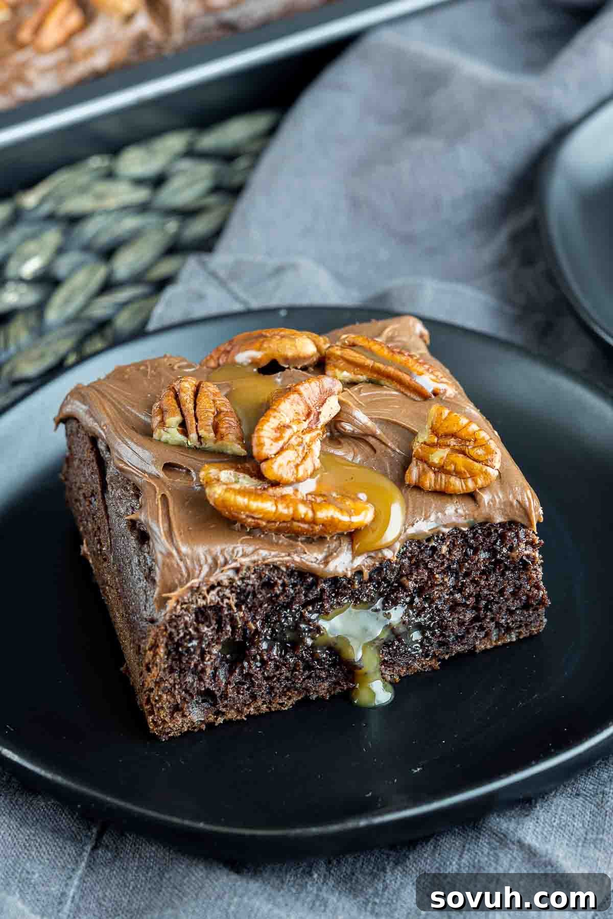 A perfectly portioned slice of Chocolate Turtle Cake on a small black plate, ready to be enjoyed.
