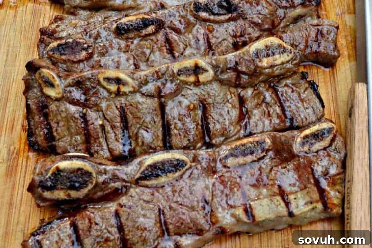 Perfectly grilled Beer and Lime Marinated Flanken-Style Short Ribs, showcasing beautiful char marks and succulent meat, presented on a rustic wooden board, ready to be enjoyed.