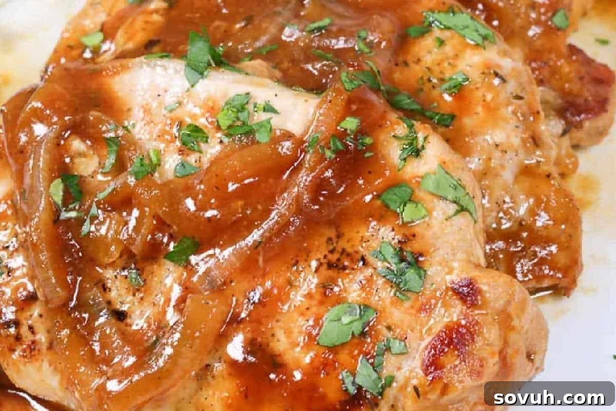 Golden pan-seared pork chops, beautifully garnished with fresh chopped parsley and a rich, beer-based sauce, ready for serving.