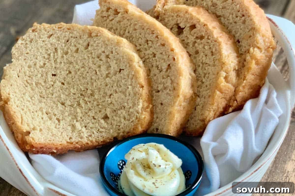 Warm, freshly baked Beer Bread, sliced and presented in a rustic basket on a white cloth, accompanied by a small bowl of creamy butter, ready for serving.