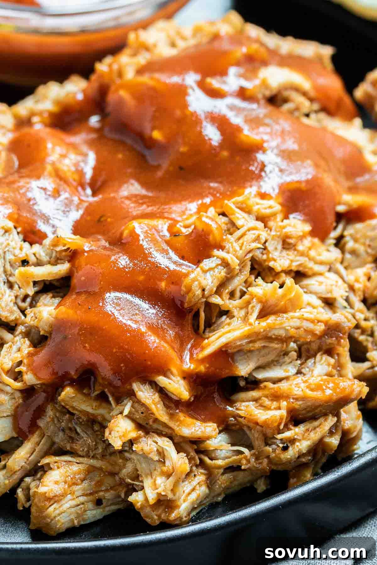 Close-up of succulent Instant Pot Pulled Pork with a generous drizzle of BBQ sauce, highlighting its tender texture.