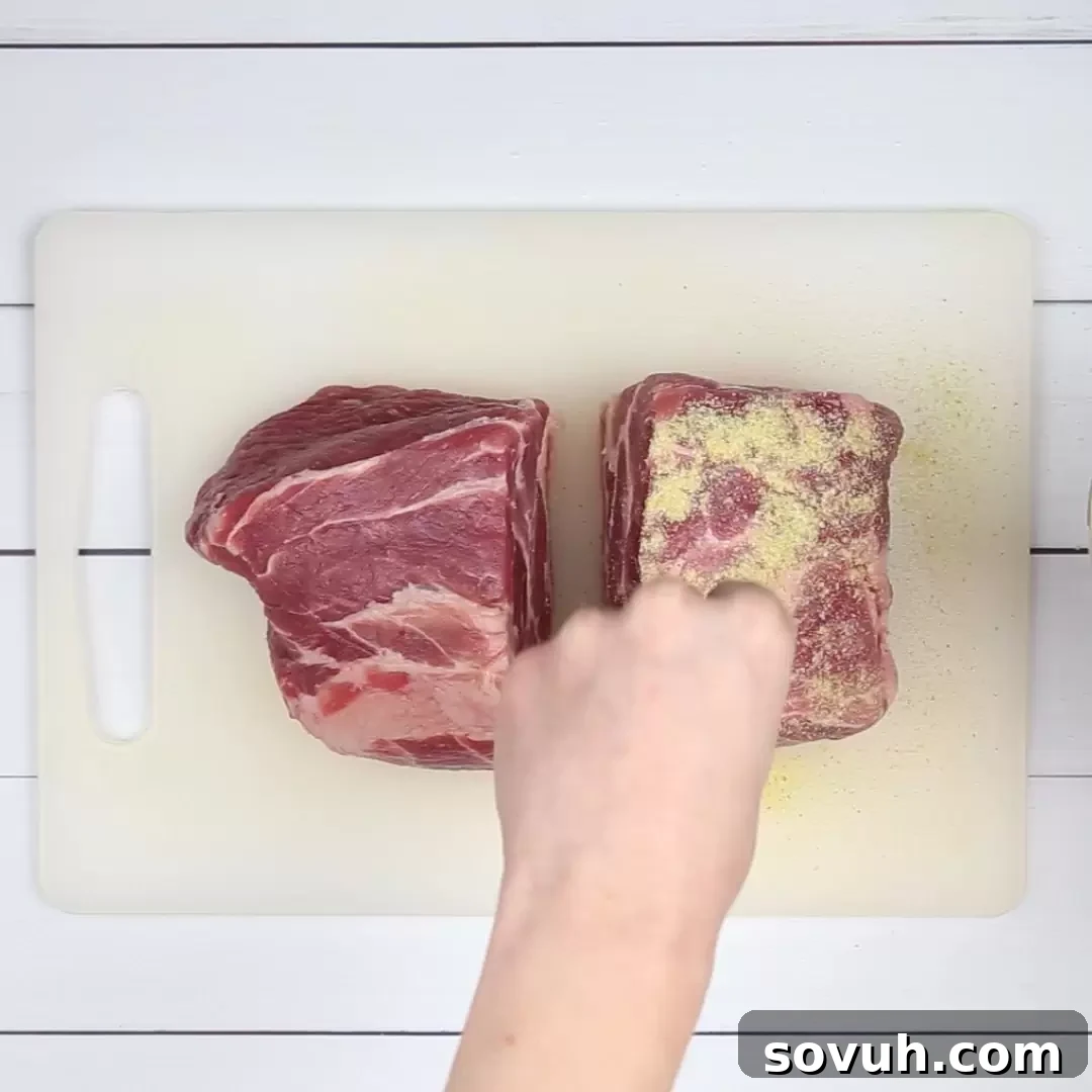 Seasoning a pork shoulder with a homemade dry rub to prepare for Instant Pot Pulled Pork, ensuring even coverage.