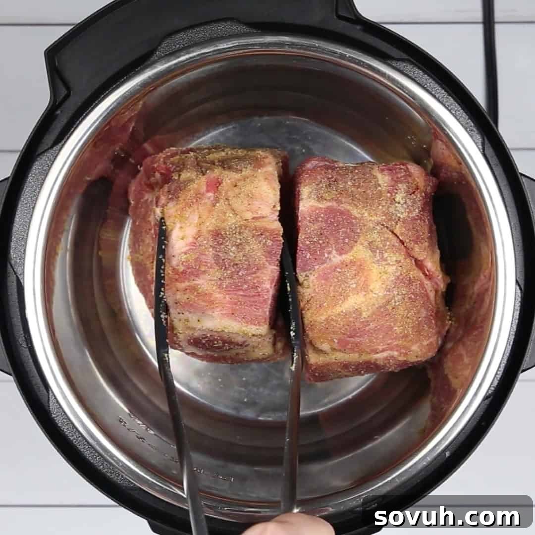 Adding the seasoned pork shoulder, a generous amount of BBQ sauce, and water into the pressure cooker for Instant Pot Pulled Pork.