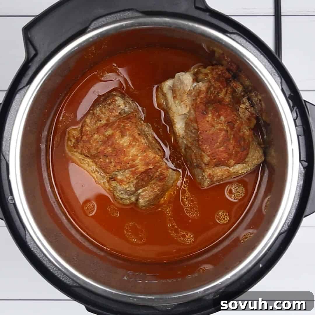 Perfectly cooked Instant Pot Pulled Pork submerged in its flavorful BBQ sauce within the pressure cooker pot, ready for shredding.