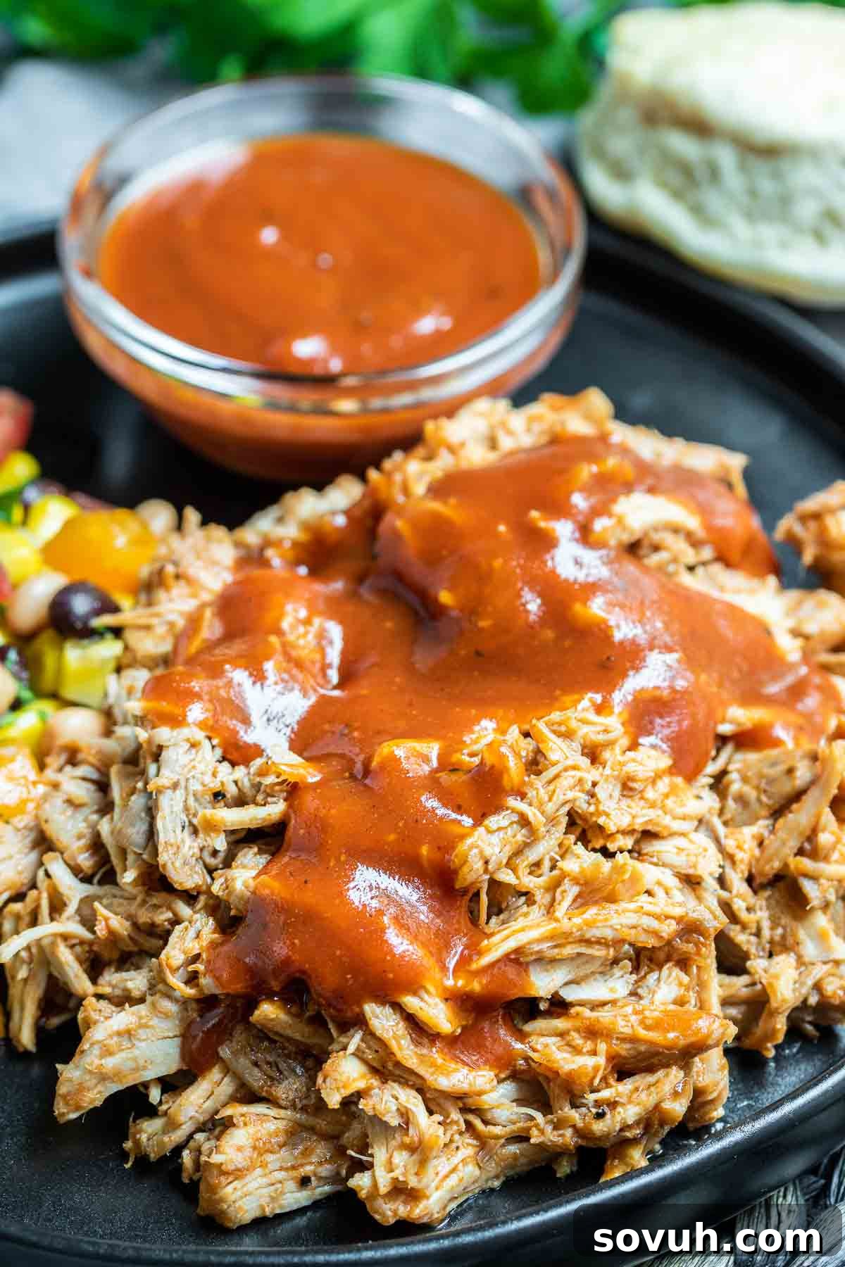 Perfectly cooked Pressure Cooker Pulled Pork presented on a plate with BBQ sauce artfully swirled in the background.