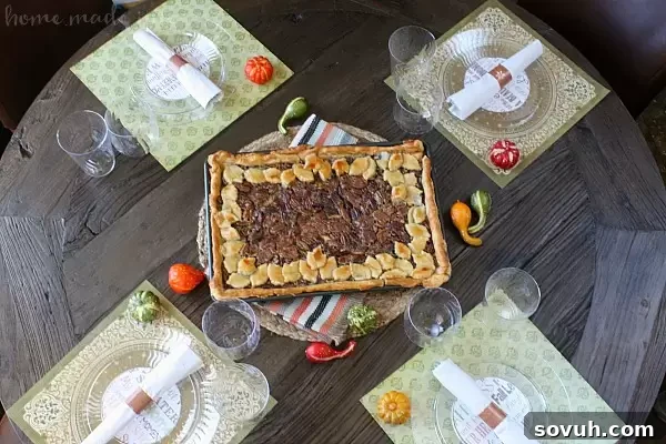 A beautifully presented Pecan Slab Pie, adorned with delicate fall leaf crust cutouts, sitting on an elegantly set table, ready for holiday serving.