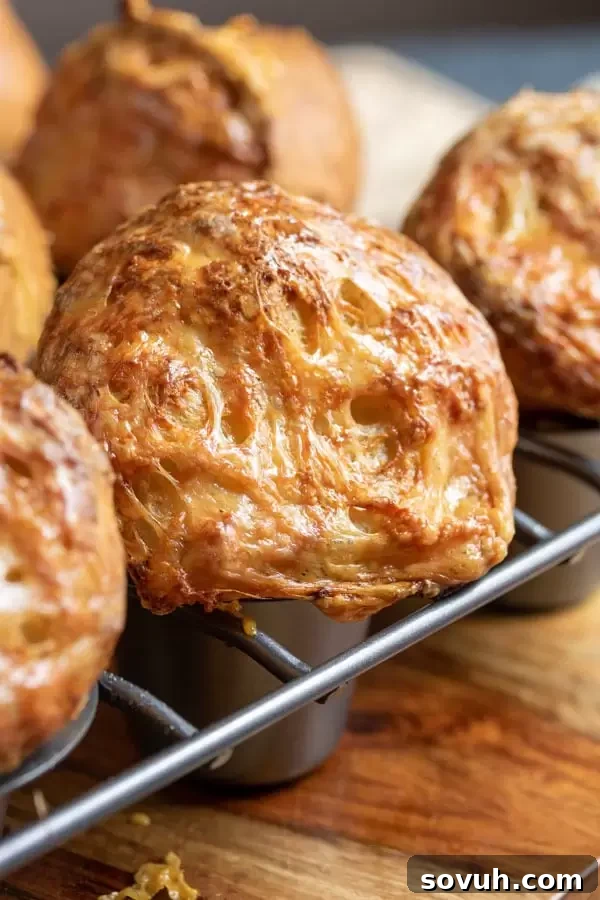 Close-up of Gruyere Popovers baking in a popover pan, showcasing their dramatic rise and golden-brown tops.