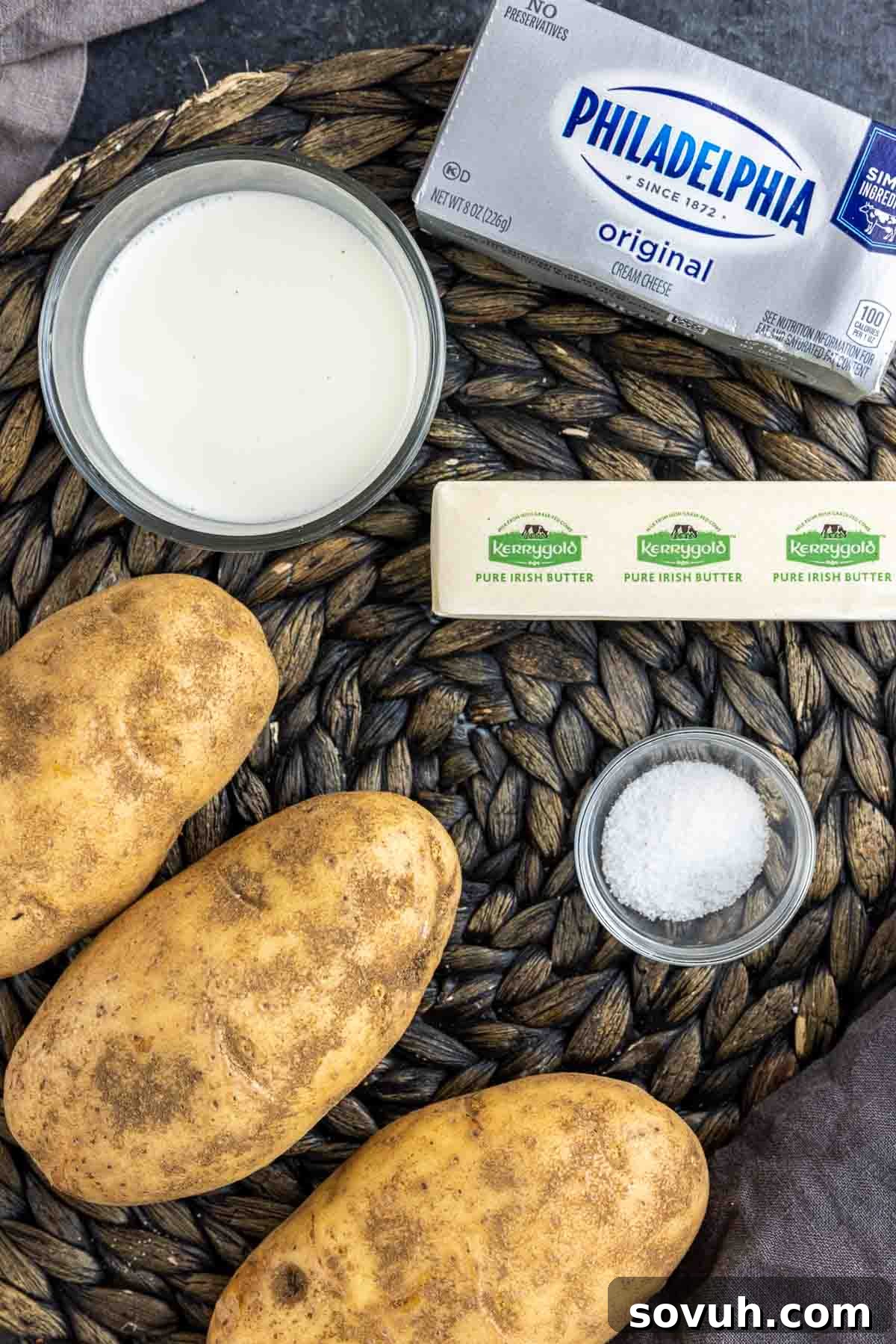 Fresh ingredients laid out for making creamy mashed potatoes, including potatoes, butter, milk, and cream cheese.