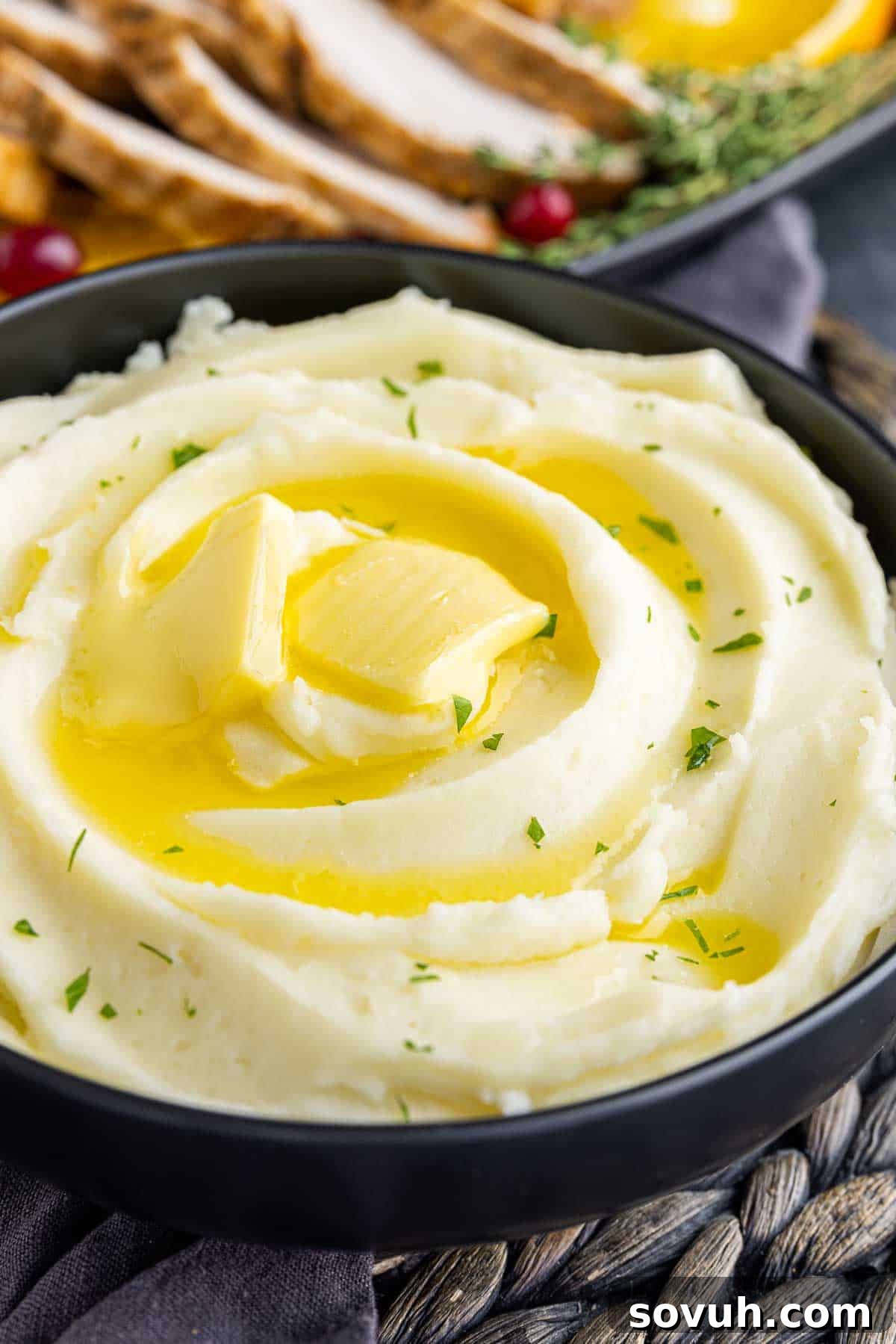A bowl of Not Your Mom's Mashed Potatoes, garnished with a pat of butter and fresh parsley.