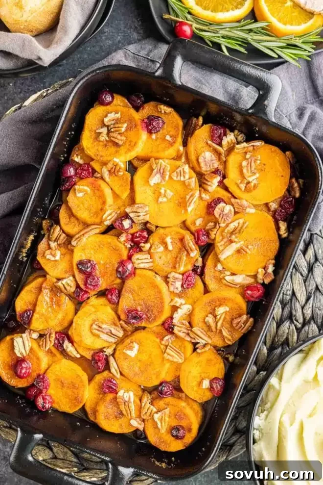 A festive Cranberry Sweet Potato Casserole in a black casserole dish, garnished with chopped pecans, ready for a holiday meal.