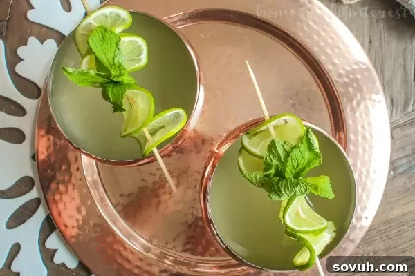 A single Champagne Moscow Mule, beautifully garnished with lime and mint, inviting guests to celebrate with this fizzy ginger cocktail.