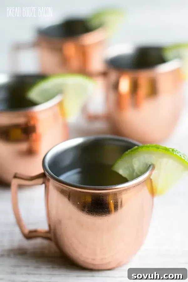 Close-up of Moscow Mule Jello Shots in mini copper mugs, garnished with lime wedges, ready for enjoyment.