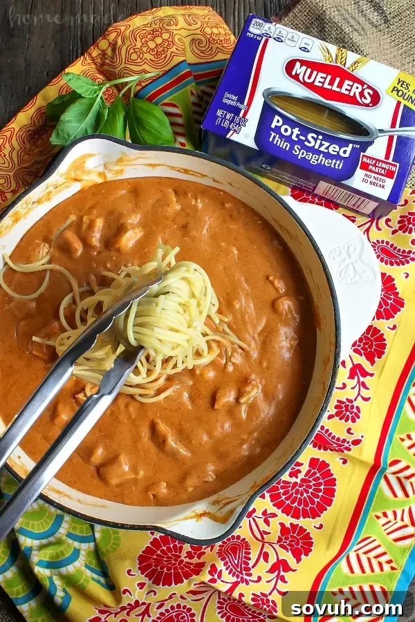 The cooking process of Chicken Enchilada Skillet Spaghetti, showing the spaghetti being added to the rich, creamy chicken enchilada sauce in a skillet, ready to be tossed and served.