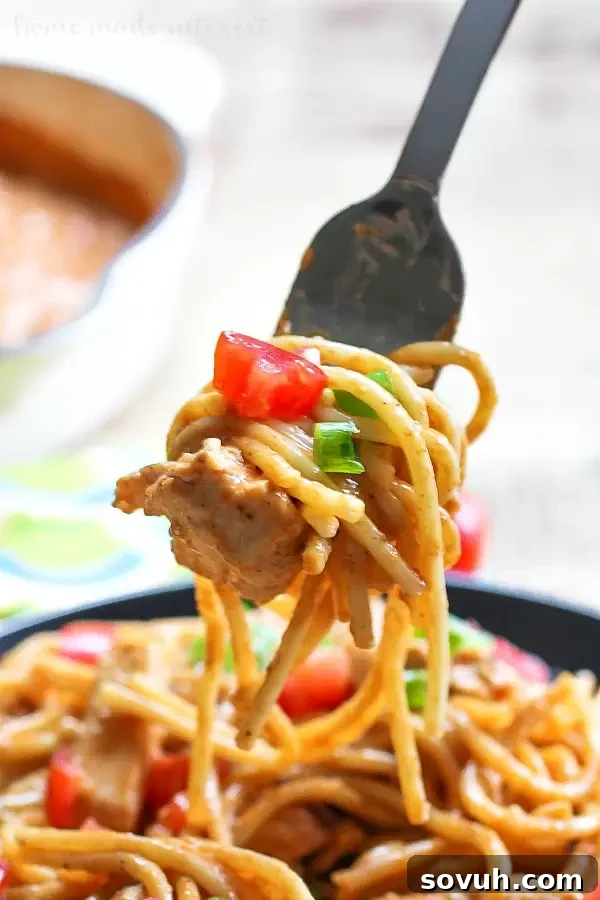 A forkful of delicious Chicken Enchilada Skillet Spaghetti, highlighting the perfect blend of creamy sauce, tender chicken, and spaghetti, ready to be enjoyed.