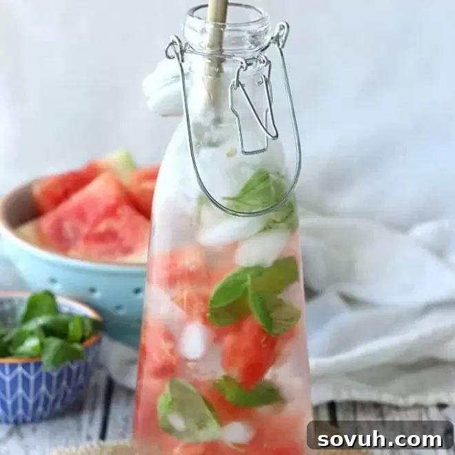 Glass bottle filled with ice, basil, and watermelon