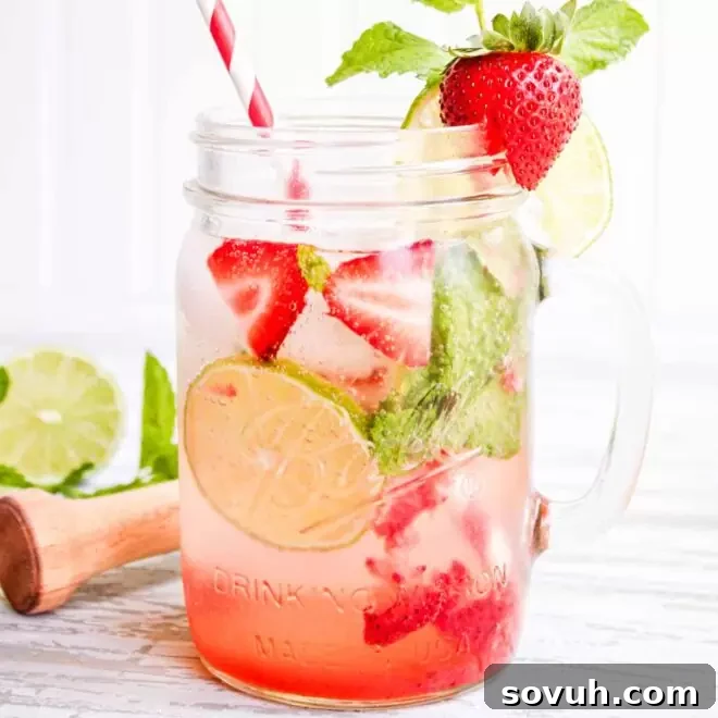 Strawberry mojito mocktail in a mason jar with limes and strawberries.
