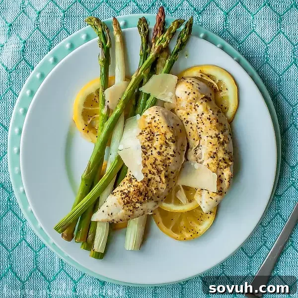 Close up of perfectly cooked sheet pan lemon chicken and tender-crisp asparagus served on a white plate