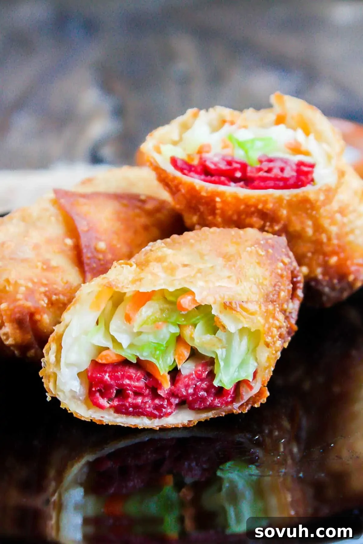 Close-up of a perfectly fried and halved Irish egg roll, revealing the golden-crisp wrapper and a flavorful interior of corned beef, cabbage, and carrots.