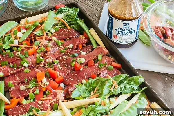Sheet Pan Beef Teriyaki ready to cook, with raw beef strips and fresh Asian vegetables arranged on a baking sheet.