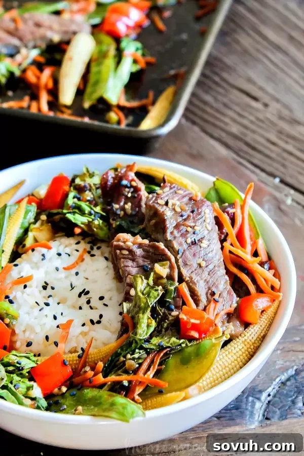Close-up of a serving of Sheet Pan Beef Teriyaki in a bowl, garnished with green onions.