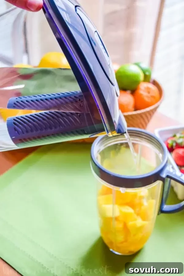 Water being added to mango cubes for mango popsicles