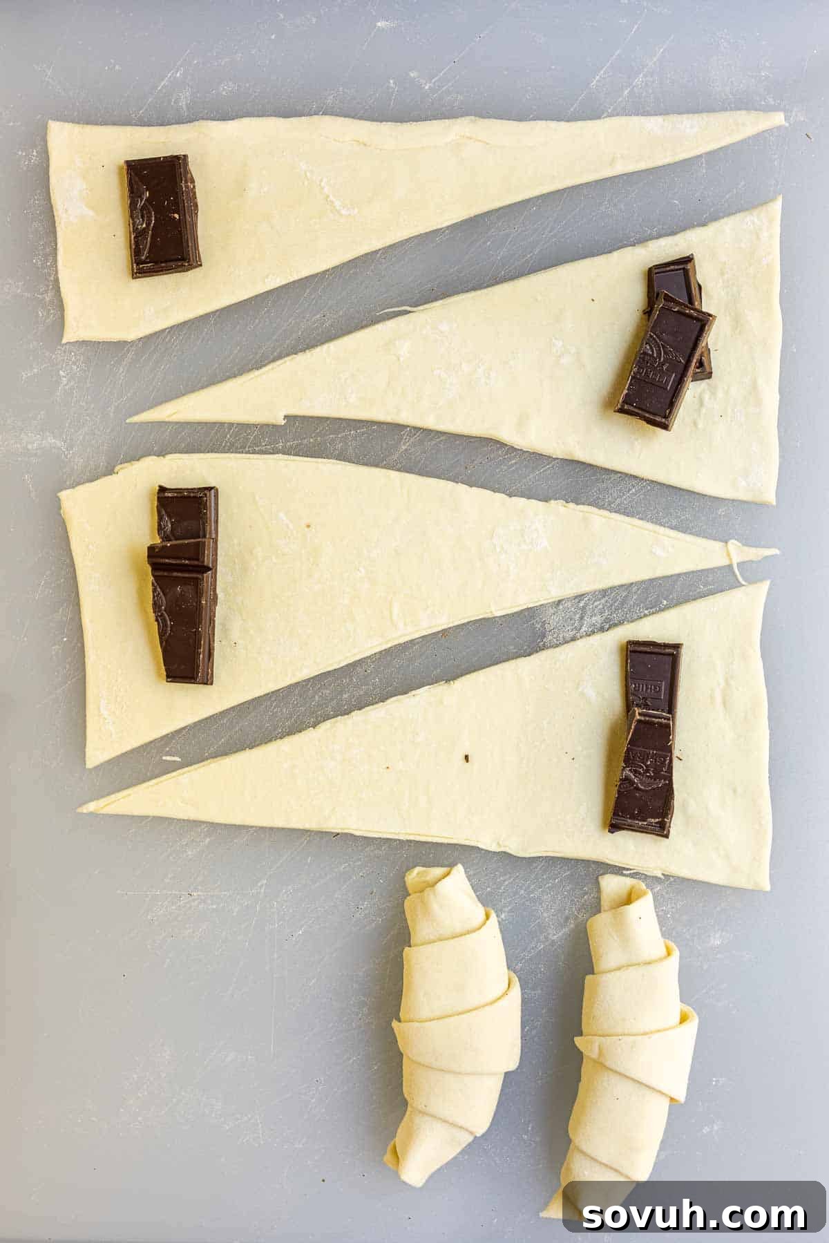 Close-up of puff pastry dough being cut into triangles for chocolate croissants