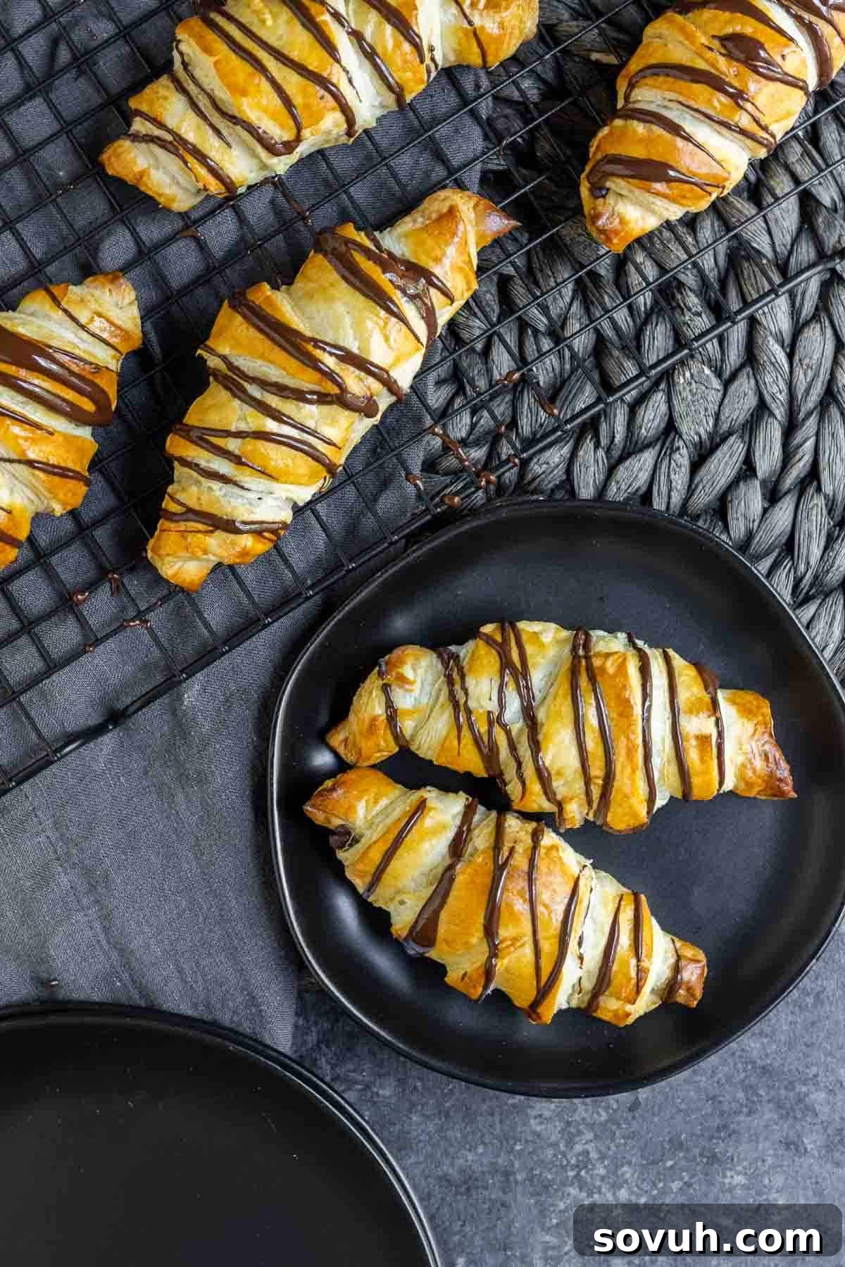 Easy Chocolate Croissants cooling on a rack and arranged on a plate.
