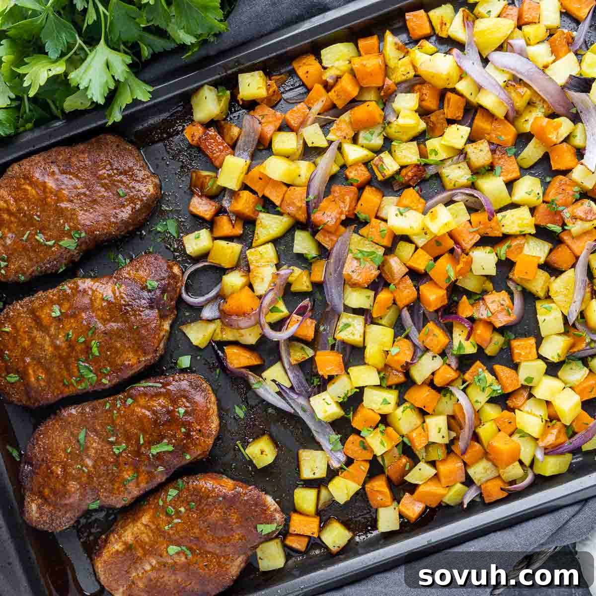 Close-up of Sheet Pan Spicy BBQ Pork Chops and Potatoes, showcasing tender pork chops coated in spicy BBQ sauce alongside roasted sweet and Yukon Gold potatoes, garnished with fresh cilantro.