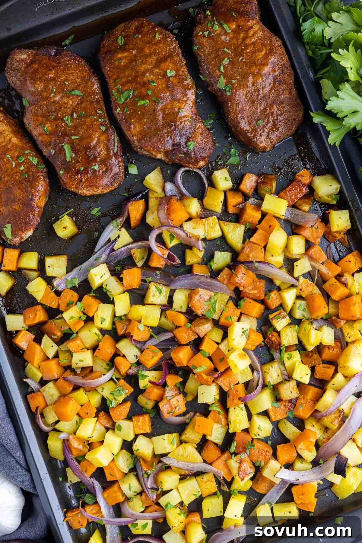 Sheet Pan Spicy BBQ Pork Chops and Potatoes cooking in an oven, showcasing the vibrant colors of the potatoes and the rich glaze on the pork chops.
