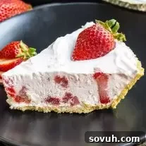 slice of Frozen Strawberry Pie on a black plate with fresh strawberries on top