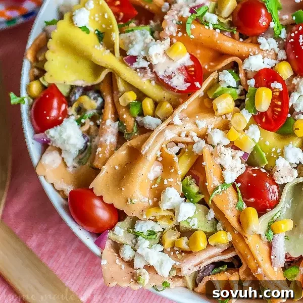 A close-up of Mexican Pasta Salad, showcasing multi-colored pasta and fresh ingredients, dressed with a creamy chipotle lime sauce, ready for serving at a summer gathering.