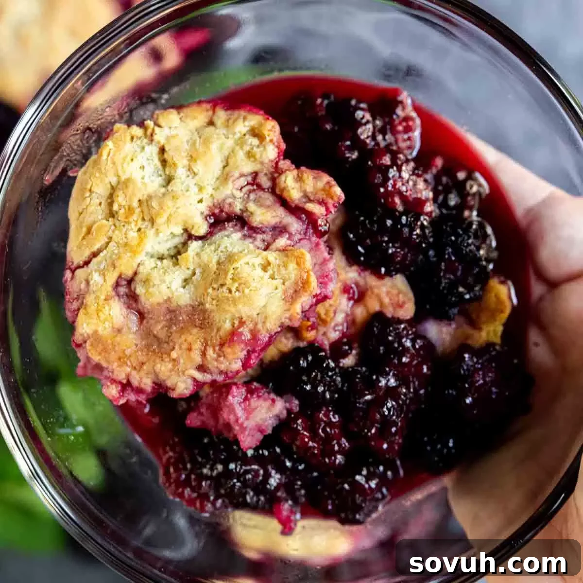 holding a bowl of easy blackberry cobbler with dough in focus