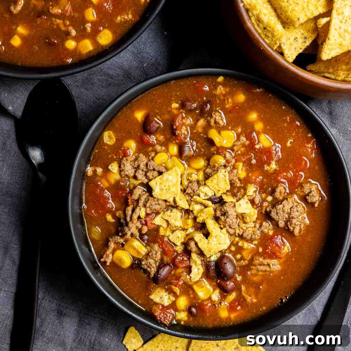 A steaming bowl of Instant Pot Taco Soup, richly garnished with fresh cilantro and sour cream, surrounded by crispy tortilla chips and corn tortillas.