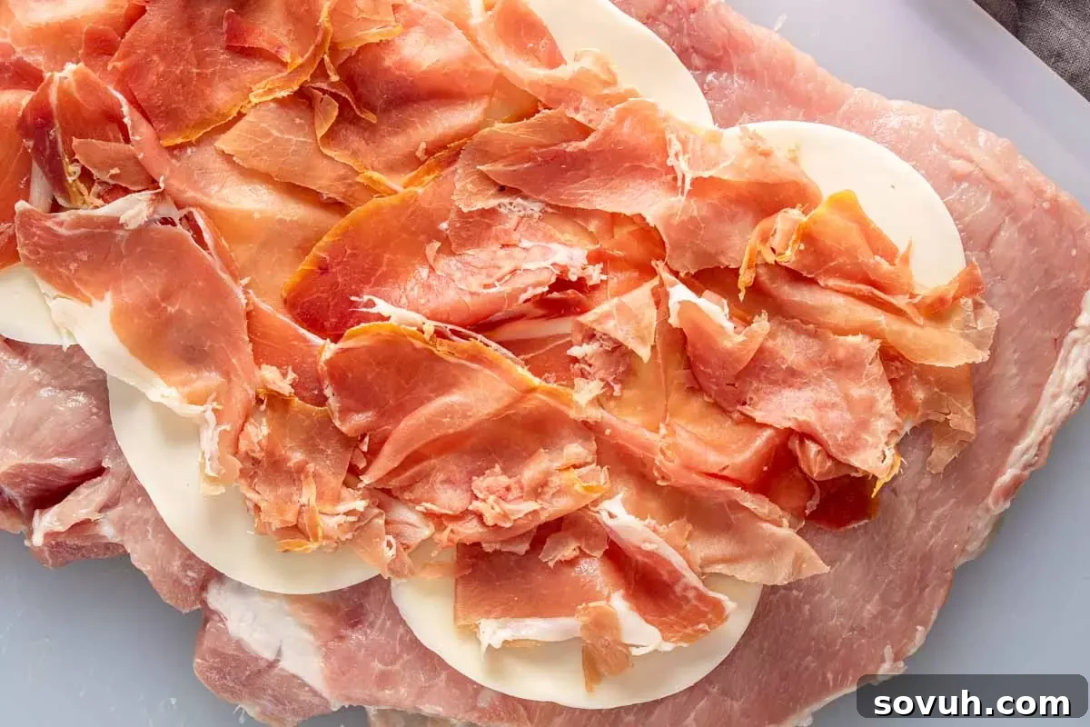 A butterflied pork loin laid flat on a cutting board, ready to be stuffed with provolone and prosciutto. This image captures the preparation stage of the recipe.