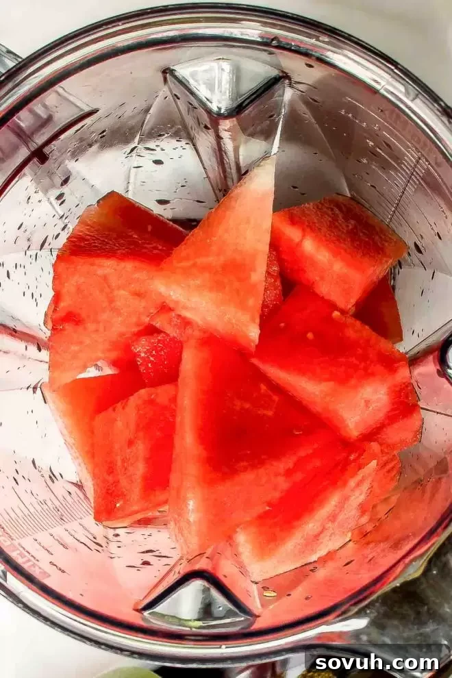 Fresh watermelon chunks being added to a blender for making the Frozen Watermelon Cocktail