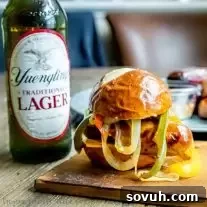 Beer Brat Sliders, a fantastic grill recipe for summer parties, featuring beer-infused grilled bratwurst on pretzel buns with beer braised onions and cheddar cheese.