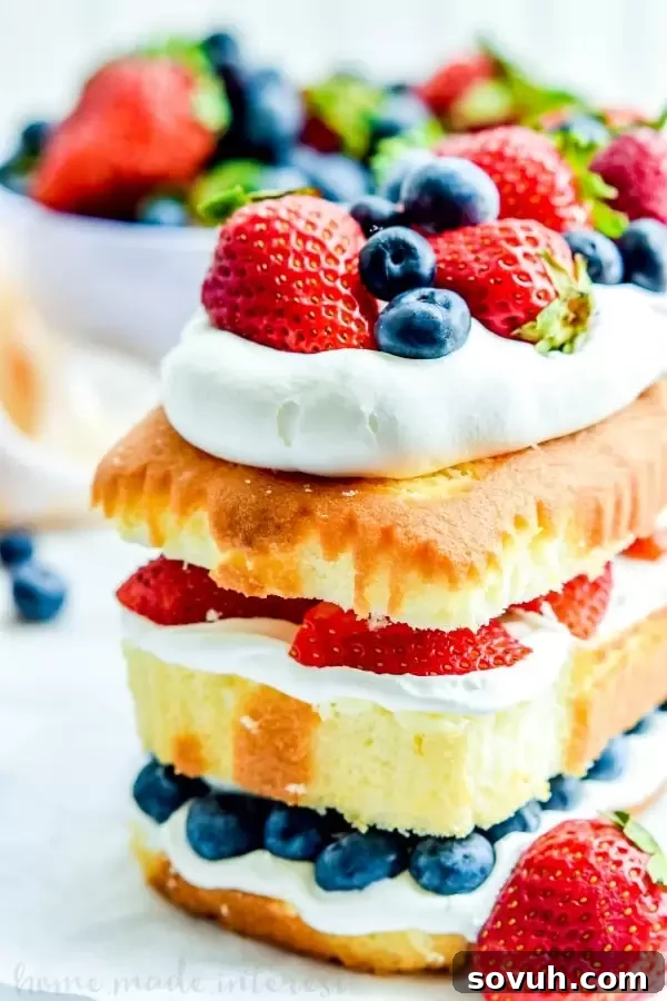 A slice of No Bake Red White and Blue Cake, showcasing its vibrant layers of cake, whipped topping, blueberries, and strawberries. This patriotic dessert is perfect for Memorial Day, 4th of July, and Labor Day celebrations, offering a refreshing and easy treat.