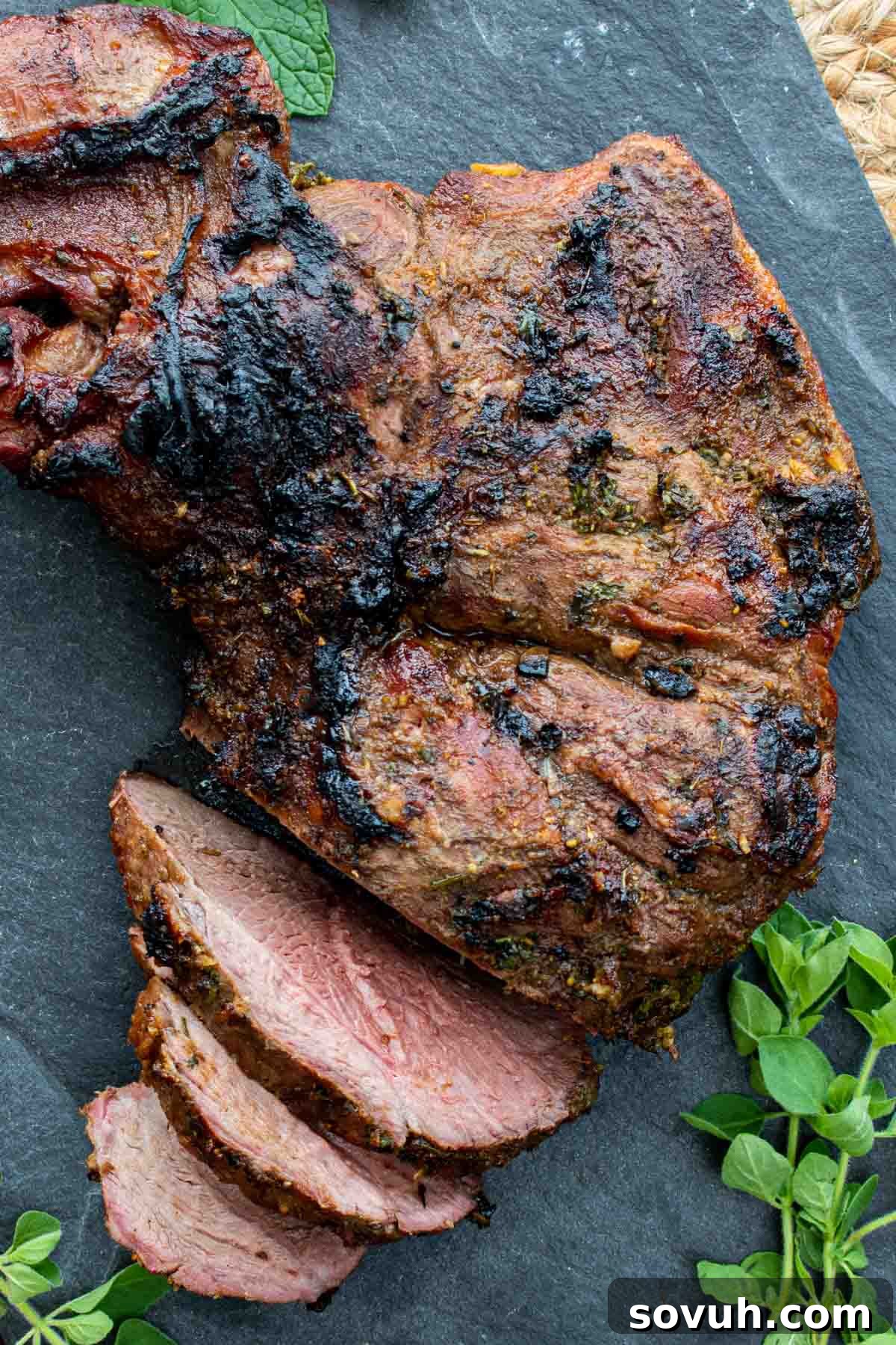 sliced grilled leg of lamb on a black cutting board