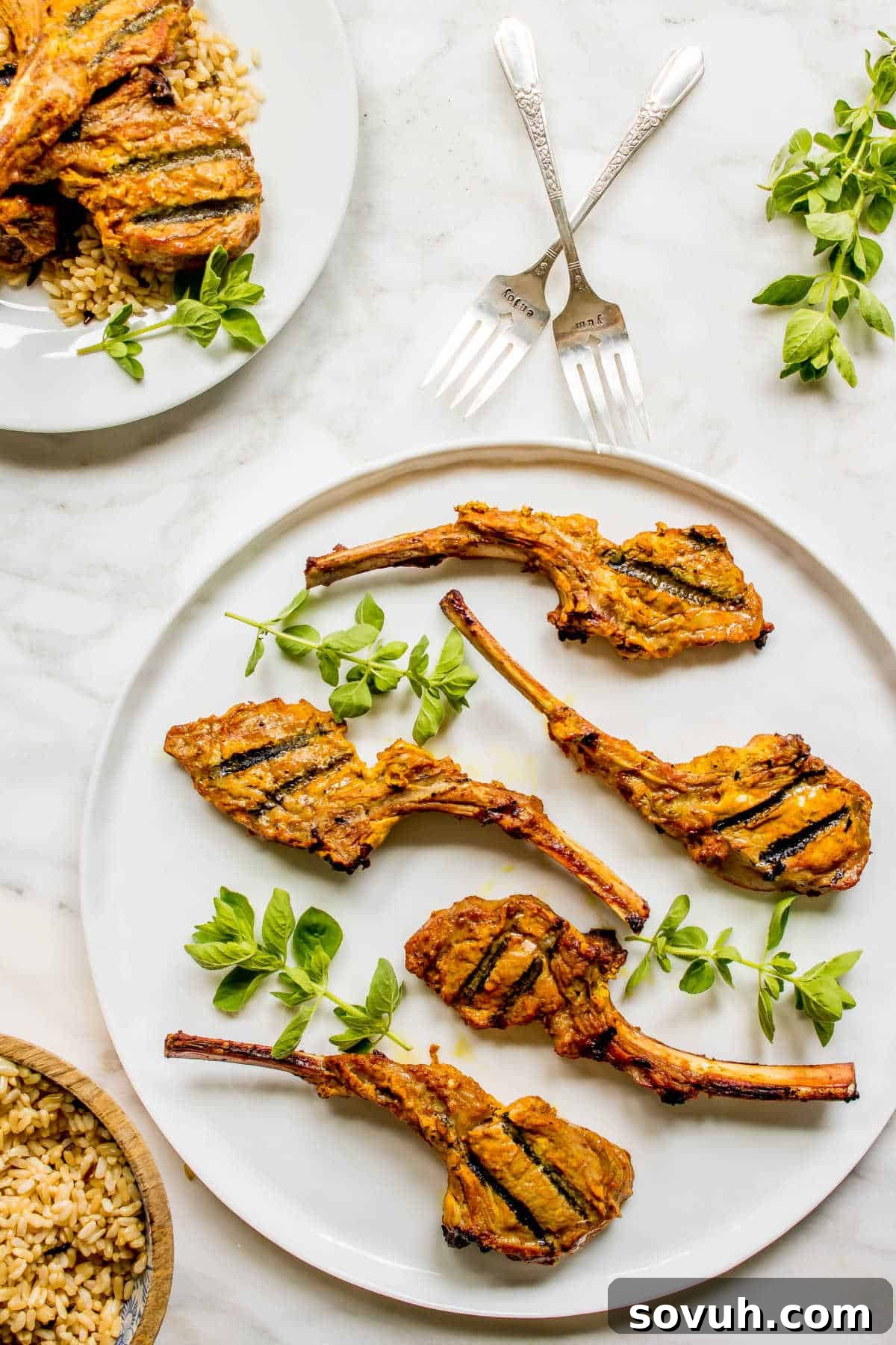 Beautifully grilled Tandoori Lamb Chops arranged on a round platter with fresh herbs for garnish.