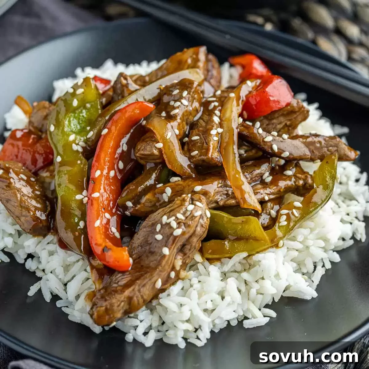 Plate with Easy Pepper Steak over fluffy white rice, ready to be enjoyed.