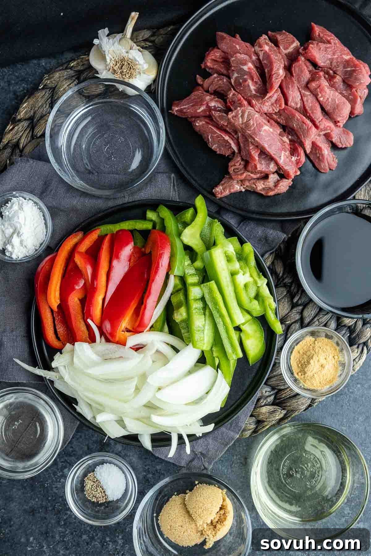 A collection of fresh ingredients laid out for Easy Pepper Steak preparation, including beef, bell peppers, soy sauce, and spices.