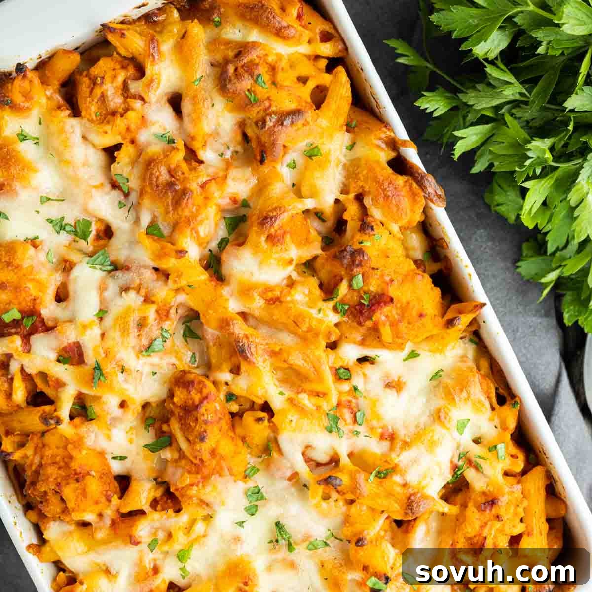 Cheesy Chicken Parm Bake 2 Delicious Chicken Parmesan Casserole in a baking dish, garnished with fresh parsley.