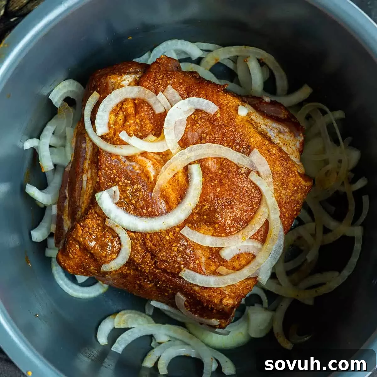 Slow cooker filled with seasoned pork shoulder and onions, ready to be cooked for Pulled Pork Tacos