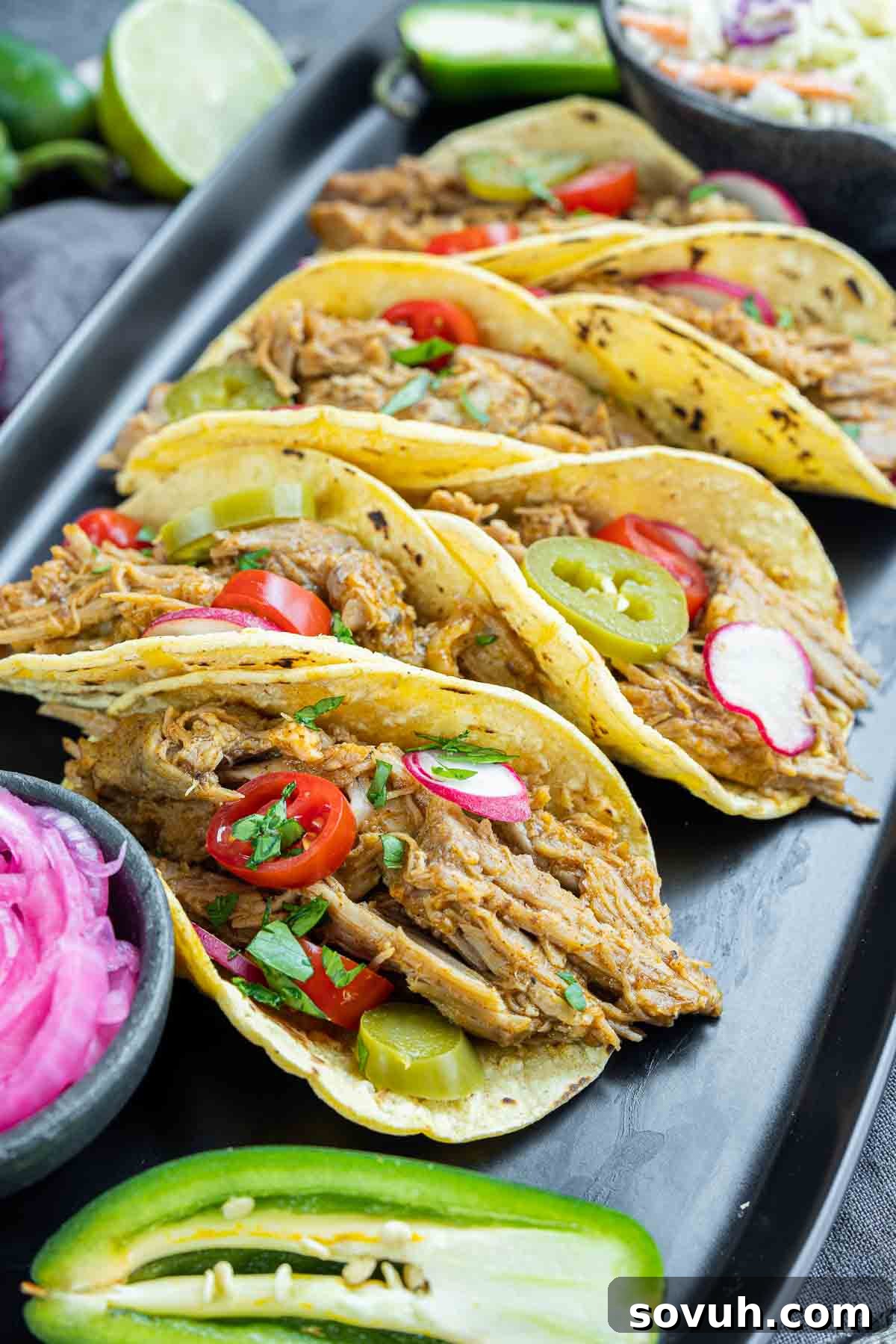 A tantalizing view of Pulled Pork Tacos generously topped and arranged on a black platter