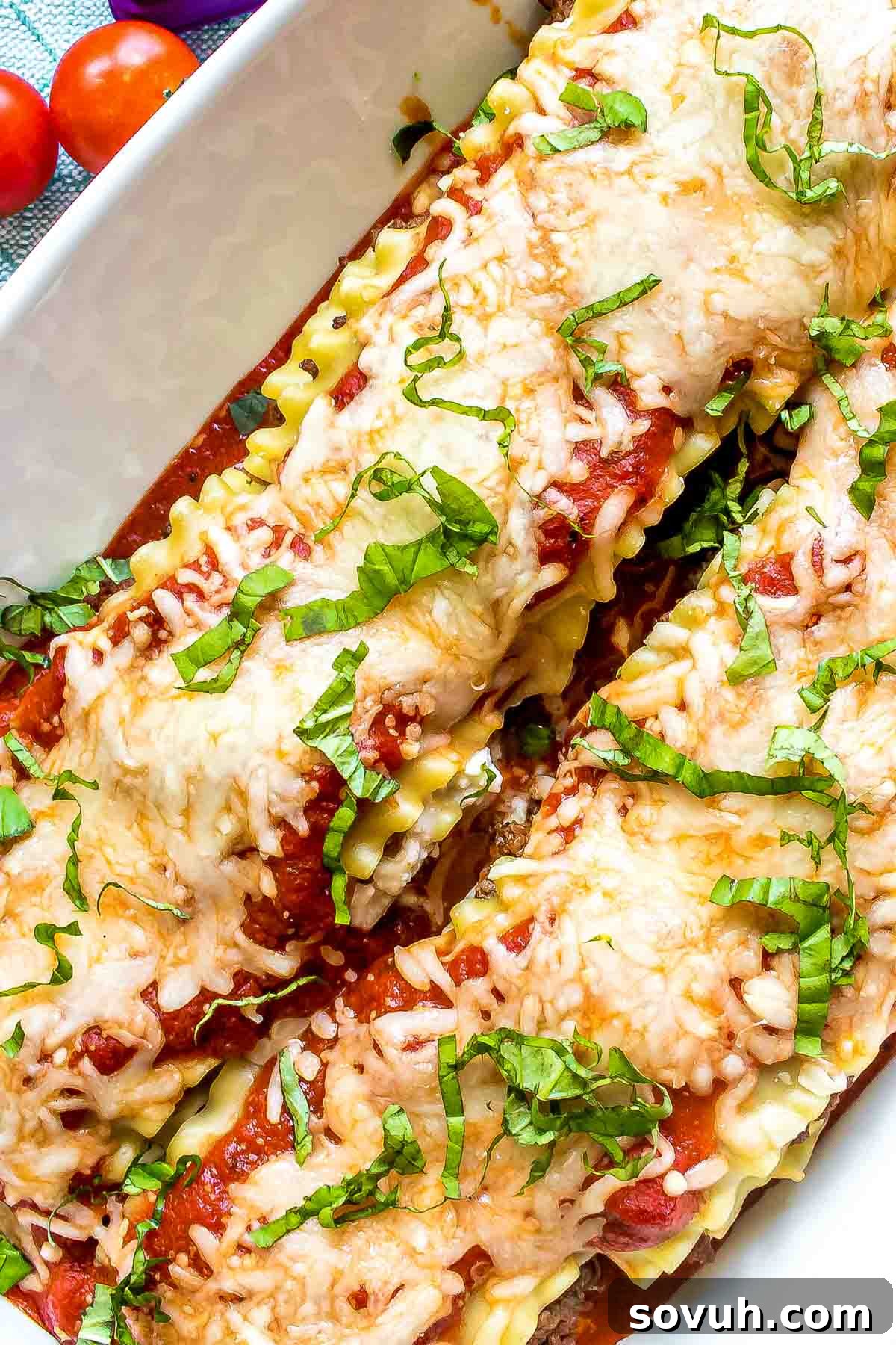Close-up of baked Lasagna Roll Ups topped with sauce and cheese, ready for serving